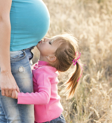 Young child kissing mother's pregnant belly