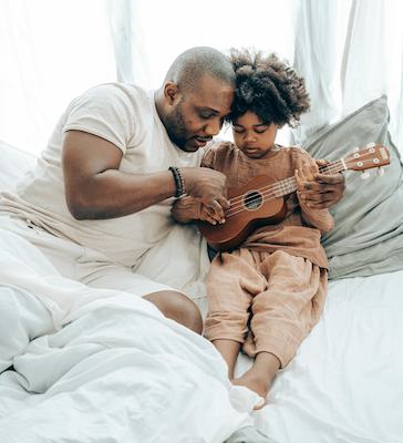 Father teaching daughter to play a small guitar